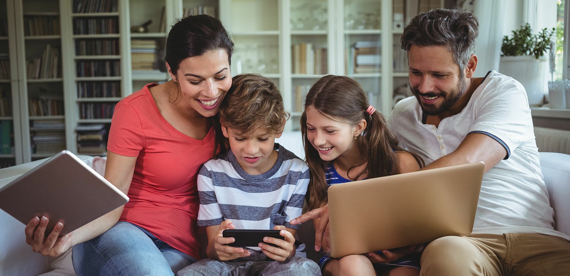 Eine Familie schaut gemeinsam auf das Handy des Sohnes