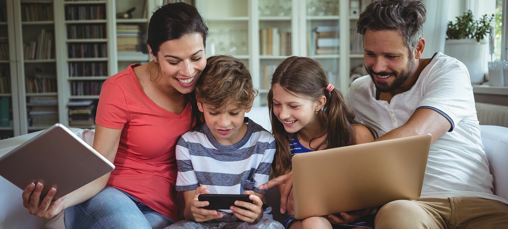 Eine Familie schaut gemeinsam auf das Handy des Sohnes