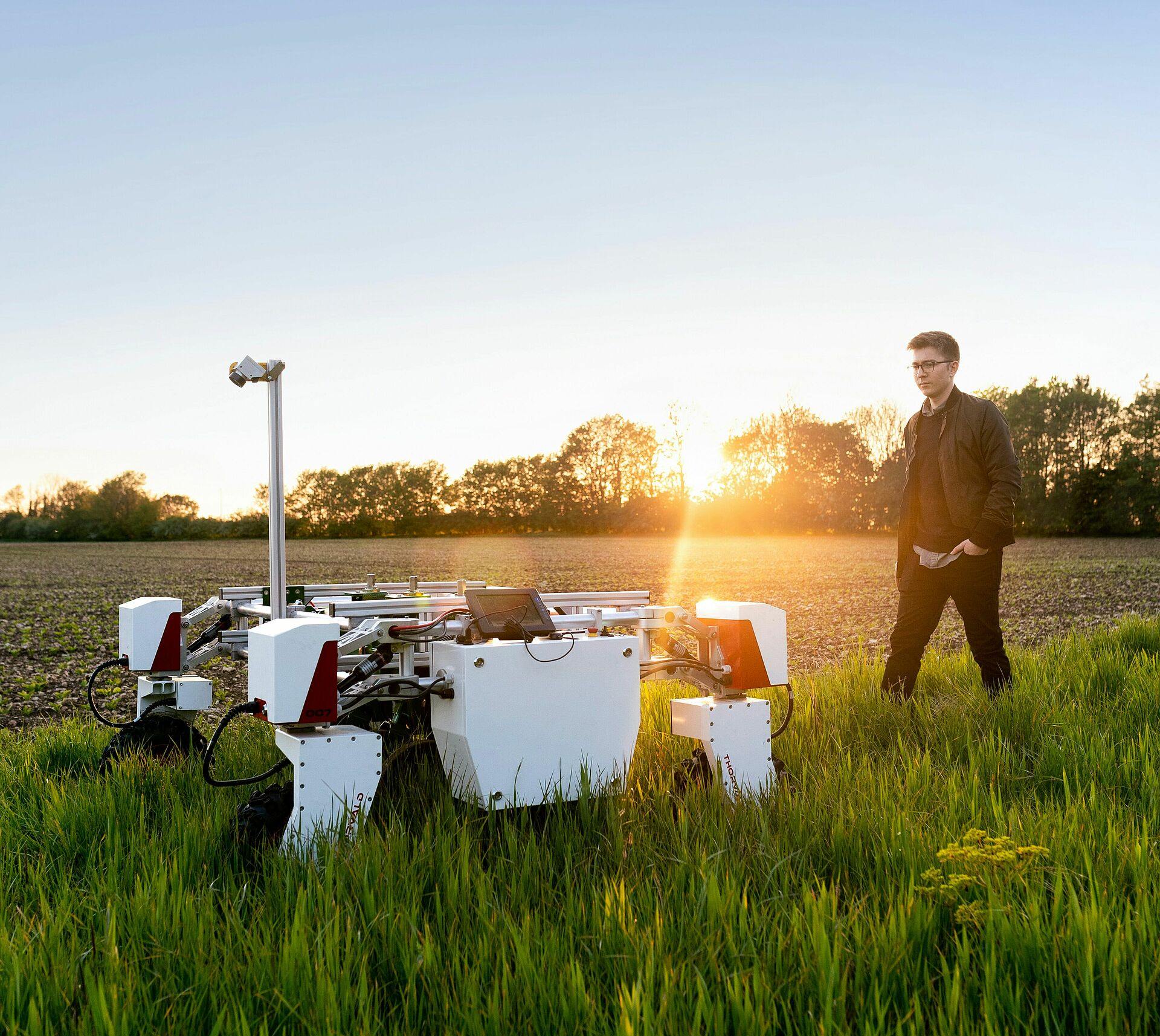Mann auf einem landwirtschaftlichen Feld mit großem Mähroboter