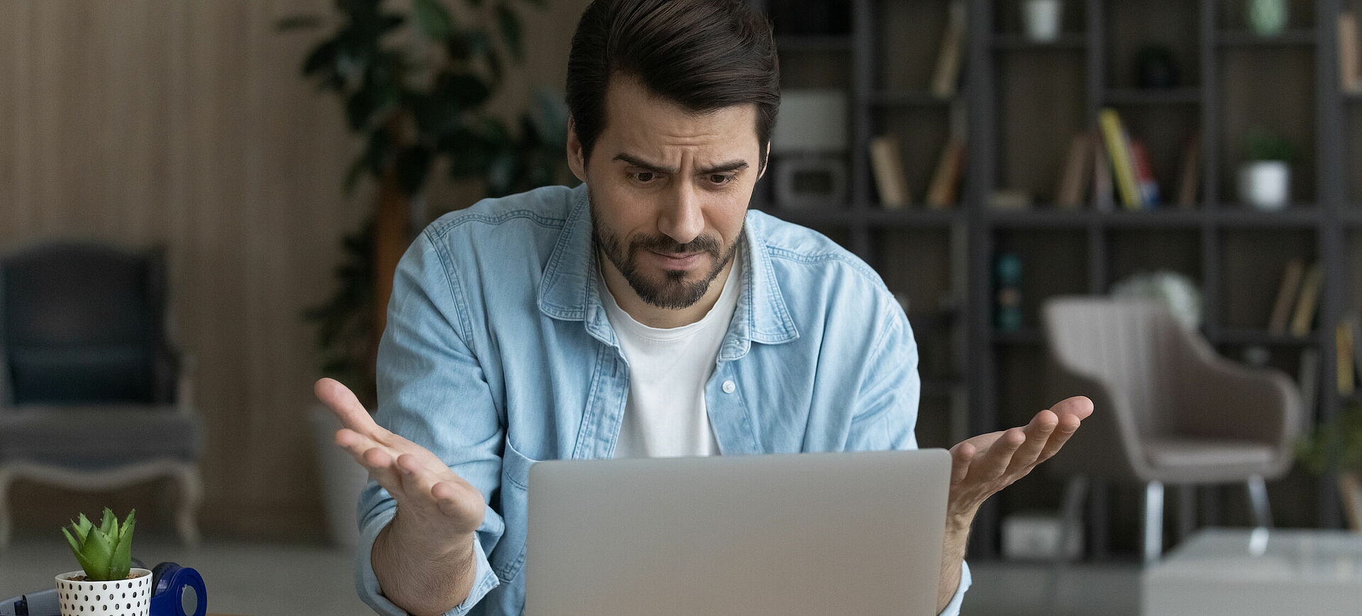 Mann sitzt verzweifelt vor dem Laptop.